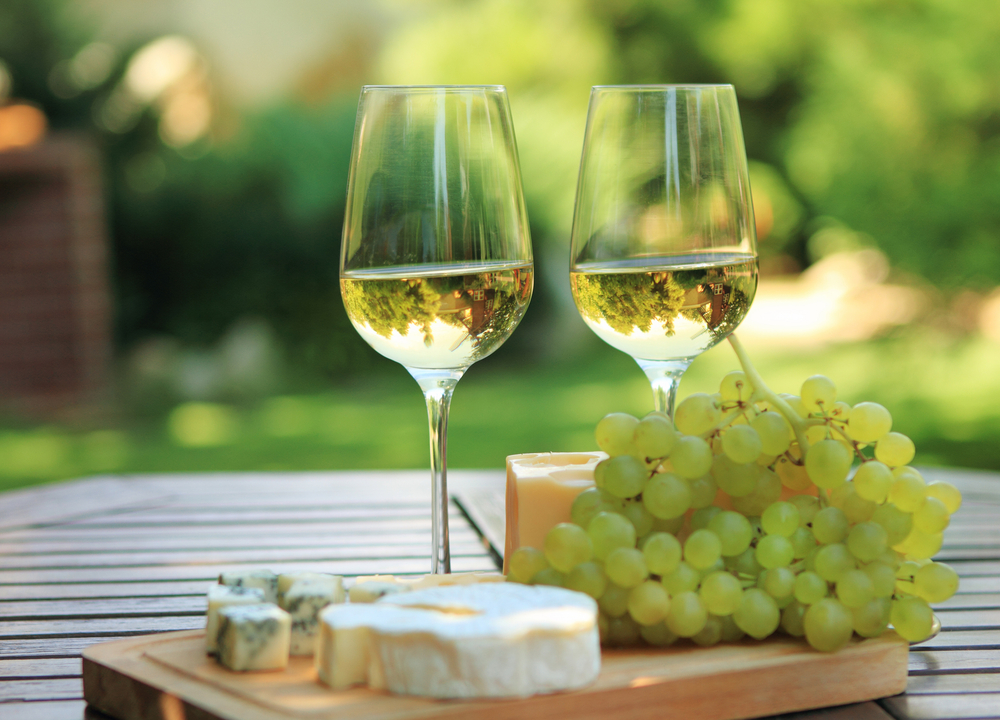 Различные сорта сыра, виноград и два бокала белого французского вина